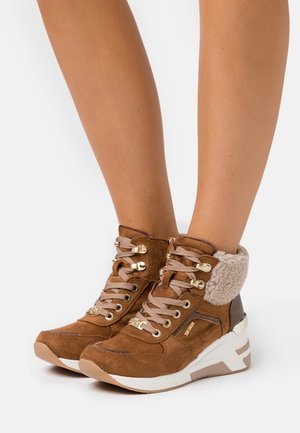 Bottes montantes en daim marron avec doublure en fausse fourrure, accents métalliques et lacets beige. Dotées d'une semelle compensée avec un panneau latéral texturé.