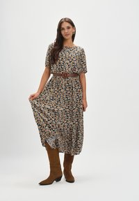 Kwiatowa sukienka maxi o czarnym tle, pomarańczowe i białe kwiaty, krótkie rękawy, pasa w talii oraz zwiewna spódnica. Połączona z brązowymi kozakami do kolan.