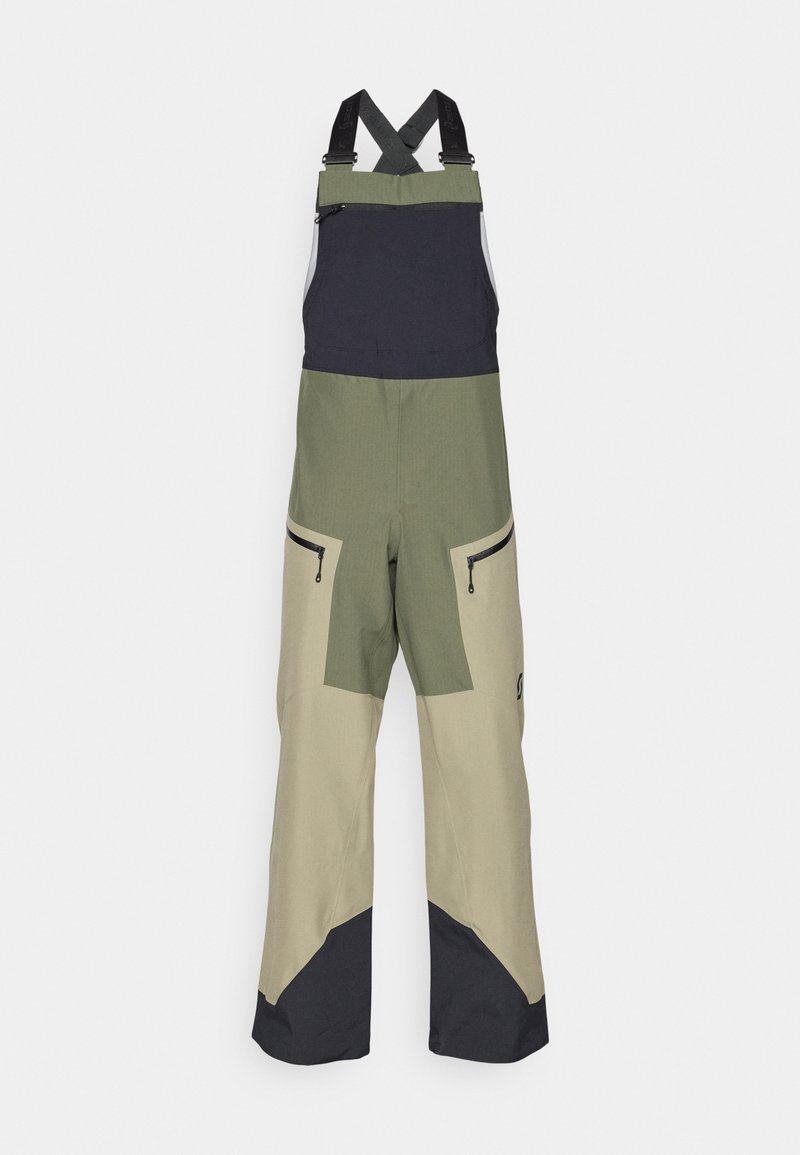 Zewnętrzne spodnie ogrodnicze w kolorze zielonym, beżowym i czarnym, z regulowanymi czarnymi szelkami oraz kieszeniami zamykanymi na zamek błyskawiczny na udach.