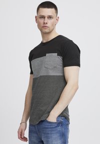 Camisa de rayas negras y grises con un bolsillo en el lado izquierdo. Mangas cortas, escote redondo y una textura suave de algodón.