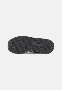 Black Adidas shoe sole with diamond-patterned tread and Adidas logo centered on the bottom, isolated on a white background.