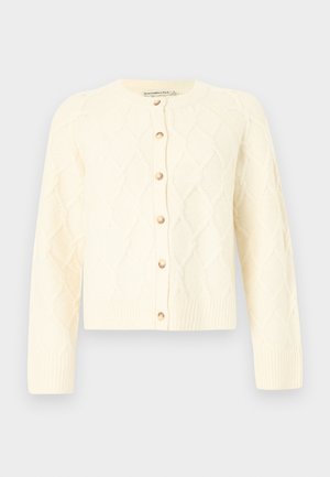 Πλεκτή ζακέτα σε κρεμ απόχρωση, με μοτίβο διαμαντιού, στρογγυλή λαιμόκοψη, μακριά μανίκια και ξύλινα κουμπιά στο μπροστινό μέρος. Μαλακή υφή.