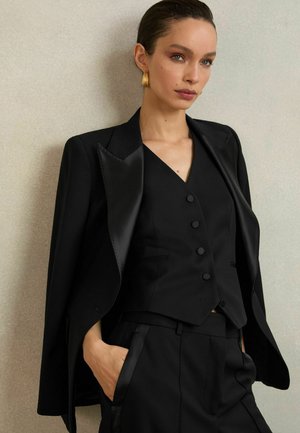 Must mustriga bleiser satenist kraega, kombineeritud sobiva vestiga, mis on varustatud nööbitava esiosaga. Sile kangas, stiilne disain.