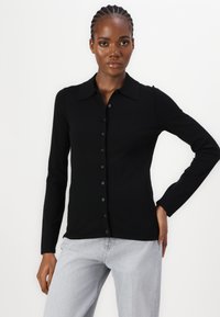 Camicia nera a maniche lunghe con bottoni, dotata di un colletto classico, realizzata in un tessuto liscio, caratterizzata da una vestibilità dritta e chiusura frontale con bottoni.