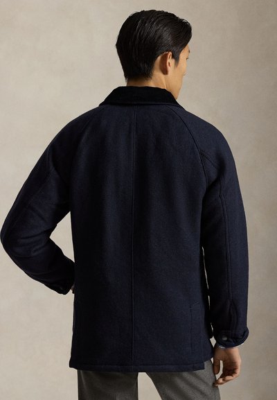 Mörkblå jacka i ullblandning med en krage i manchester, knappmanschetter och sidofickor. Texturerad yta och avslappnad passform.