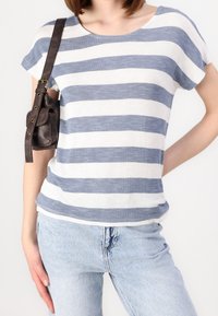 Pruhované tričko v bílé a modré barvě, krátké rukávy, kulatý výstřih. S kombinací světle modrých džínů a malou hnědou koženou taškou na rameni.