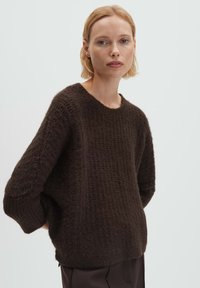 Brauner Strickpullover mit strukturiertem Muster, weit geschnittenen Ärmeln und rundem Halsausschnitt, gefertigt aus einem weichen, gemütlichen Material.