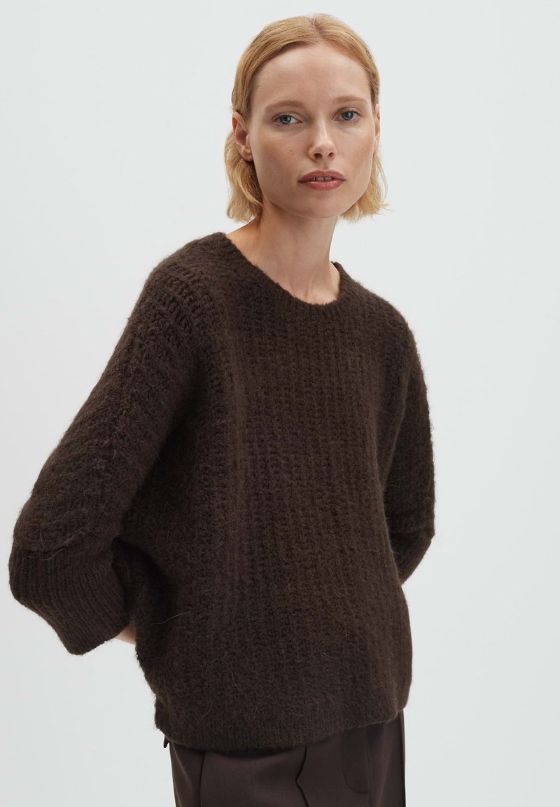 Brauner Strickpullover mit strukturiertem Muster, weit geschnittenen Ärmeln und rundem Halsausschnitt, gefertigt aus einem weichen, gemütlichen Material.