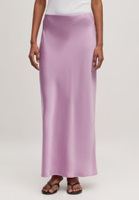Jupe maxi en satin lavande avec une texture lisse, taille haute et une silhouette droite, associée à des sandales plates noires.