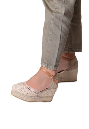 Wedge shoes with woven beige fabric upper, adjustable tan ankle strap, and a textured jute material sole for added grip and style.