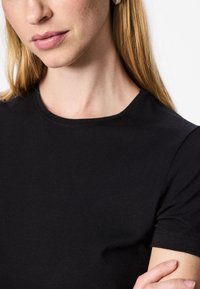 Must lühikeste varrukatega t-särk ümarate kaelustega, valmistatud pehmest, siledast kangast. Omab minimaalseid õmblusi ja kehakuju järgivat lõiget.