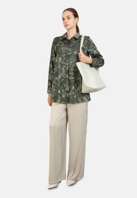 Vihreä kukkakuosinen oversized-paita, beige leveälahkeiset housut ja valkoinen olkalaukku. Asusteessa on pehmeitä tekstuureja ja rento siluetti.