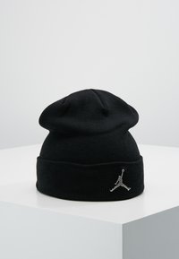 Musta neulepipo pehmeällä pinnalla, jossa on käännettävä reunus ja hopeinen Jumpman-logo edessä. Klassinen muotoilu ja yksinkertainen malli.