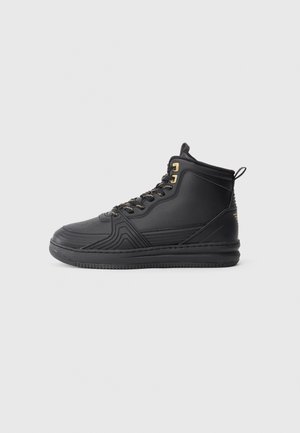 Zwarte hoge sneakers van textuur rubber en glad leer. Voorzien van gouden veterogen en een verstevigde hak. De zijkant heeft geometrische patronen.
