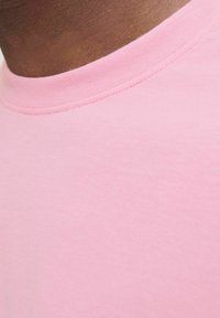 Camiseta de algodón rosa con cuello redondo, que presenta una textura suave y un minimal detalle de costura alrededor del cuello.