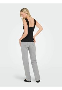 Zwarte tanktop met kanten schouderbanden, gecombineerd met grijze jeans. De top heeft een getailleerd ontwerp en een ronde rug. Platte schoenen maken de outfit compleet.