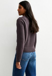 Gebreide trui met een ronde halslijn, lange mouwen en geribbelde zoom. Kleur is diep mauve. Gemaakt in combinatie met hoog uitgesneden blauwe spijkerbroeken.