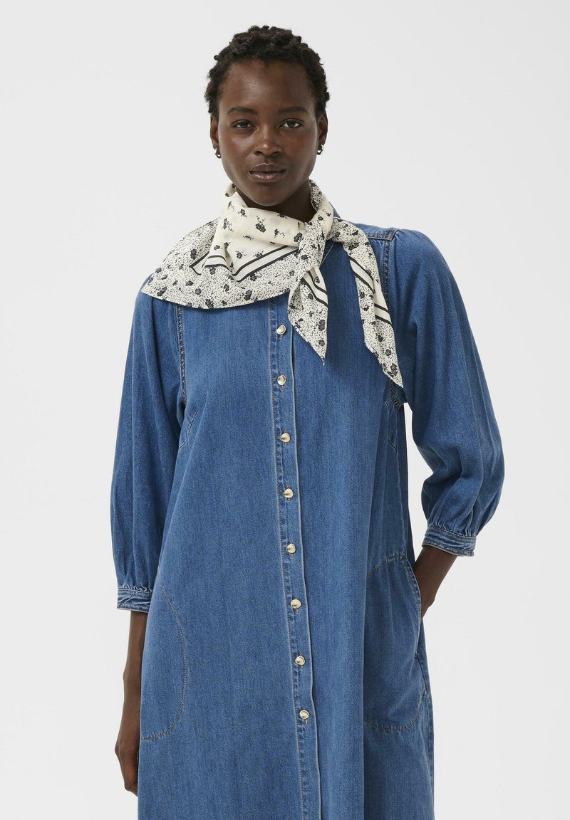 Vestito in denim con chiusura frontale a bottoni, maniche lunghe a sbuffo, tasche arrotondate e sciarpa con motivo floreale annodata al collo. Colore blu, design casual.