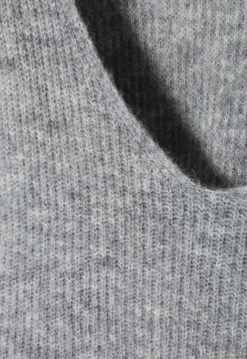 Jasnoszara, dziana tkanina o miękkiej teksturze, z niskim okrągłym dekoltem i subtelnym detalem w prążki.