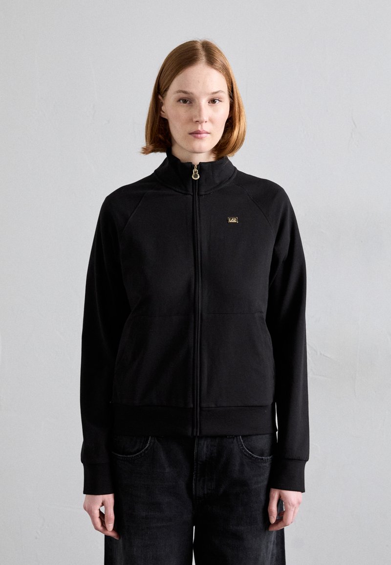 Crna zip-up dukserica s visokim ovratnikom, s zlatnim logotipom, raglan rukavima i prednjim džepovima. Glatka tekstura i usklađen dizajn.