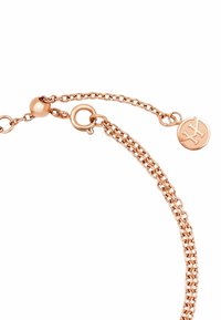 Pulsera de cadena en oro rosa con cadenas enlazadas, un charm redondo con un logo y un cierre de gancho con un detalle esférico de acento.