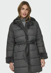 Abrigo gris acolchado con cuello y puños de pelo sintético, cinturón en la cintura, con un diseño acolchado y bolsillos laterales.