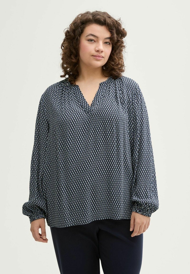 Blusa de color azul marino con un patrón geométrico blanco, escote en V y mangas largas con gather. Tejido suave y ligero con un corte holgado.