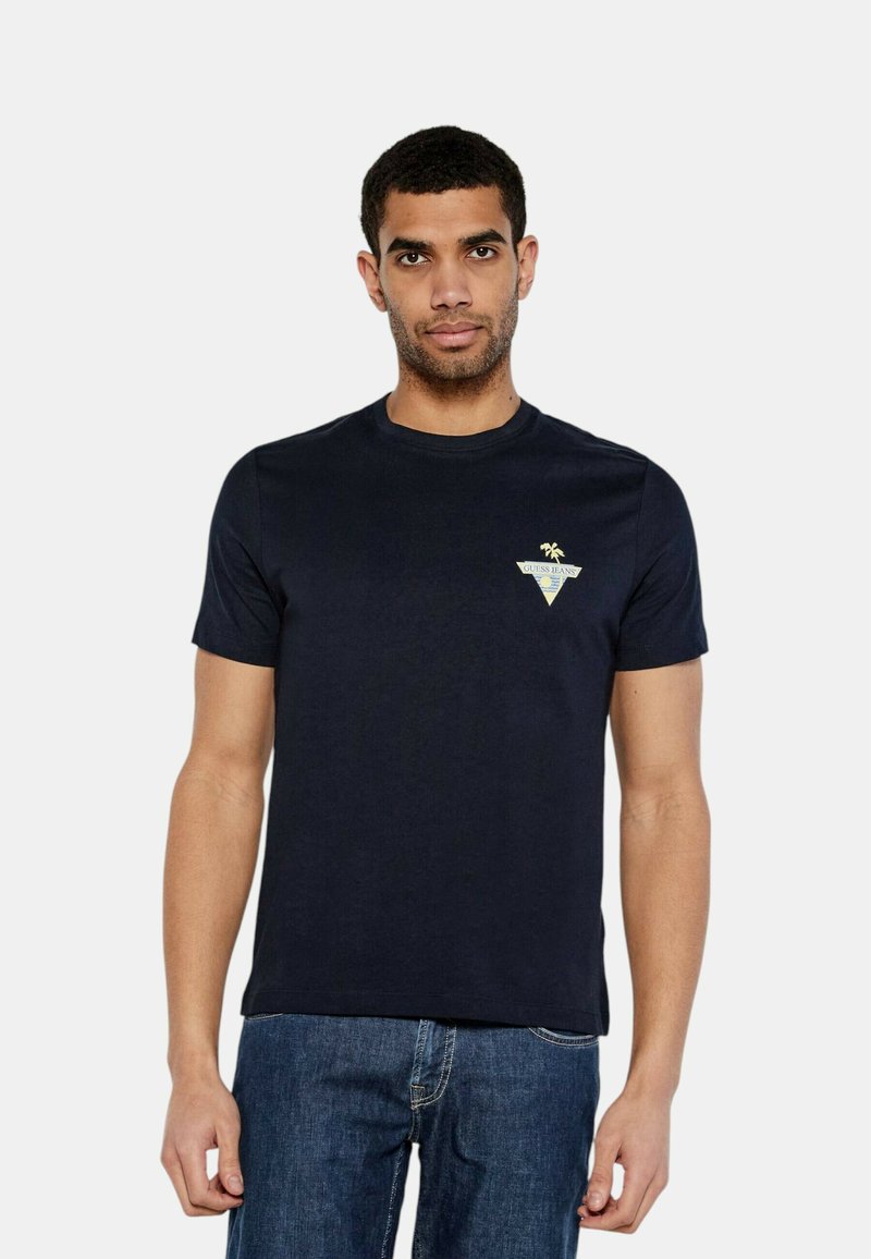 T-shirt in cotone blu navy con maniche corte, colletto girocollo e un piccolo logo a triangolo con una palma sul petto. Vestibilità casual.