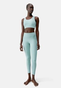Licht mintgroene activewear-set met een aansluitende sportbh en hoge taille leggings. Glad oppervlak en minimalistische naaiafwijkingen.