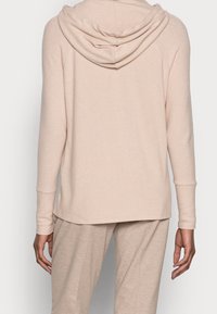 Ljusbeige hoodie i mjukt tyg, med en draperad huva, långa ärmar och en avslappnad passform med rundad nederkant.