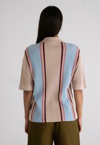 Short-sleeve polo in textured knit, featuring alternating blue, pink, and burgundy vertical stripes on a beige background.