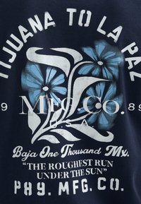 Tmavě modré bavlněné tričko s bílými a modrými květinovými motivy a textem. Design zahrnuje vintage styl tisku a tučné písmo.