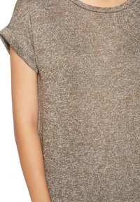 Hnědý pletený top s texturovaným, skvrnitým vzorem. Má krátké ohrnuté rukávy a kulatý výstřih. Měkký, lehký materiál.
