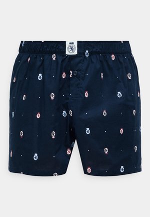 Navy blue boxer shorts in cotton blend, featuring a pattern of small logos in red and blue, with an elastic waistband and button closure.