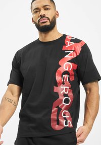 Black cotton T-shirt featuring bold red text "DANGEROUS" printed vertically on the left side. Short sleeves and crew neck design.