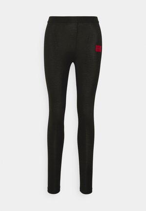 Black leggings made of smooth, stretchy fabric with a fitted design. Features a small red logo patch on the left hip.