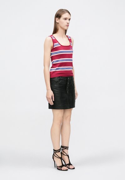 Camiseta sin mangas a rayas rojas y blancas, minifalda de cuero negra con botones al frente y sandalias negras de tacón alto con tiras.