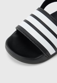 Μαύρη και λευκή σαγιονάρα με επάνω μέρος από λείο καουτσούκ με τρεις οριζόντιες ρίγες και υφασμένο μαύρο πάτο.