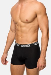 Boxer shorts de algodón negros con una cinturilla elástica de marca en blanco y negro, que ofrecen un ajuste ceñido y una textura suave.