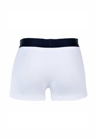Boxer shorts de algodón blanco con una cinturilla azul marino, que presentan una textura suave y un diseño ajustado, cortados a media muslo para una silueta moderna.