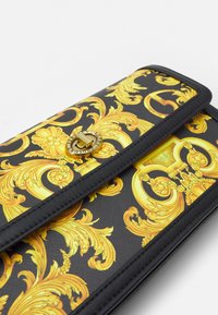 Czarna kopertówka z złotym barokowym wzorem, z teksturowanym wykończeniem i złotym okrągłym zapięciem na klamrę.