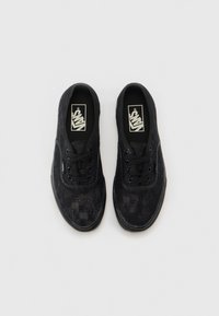 Black casual sneakers featuring a textured upper with a checkerboard pattern, black laces, and a rubber sole. Vans logo on the insole.