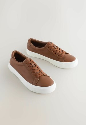 Bruine leren sneakers met witte rubberen zolen, met ronde neuzen, platte veters en een gladde textuur.