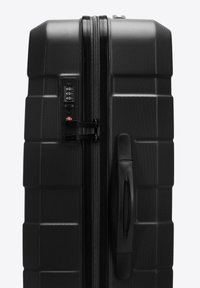 Valigia rigida nera con superficie testurizzata, chiusura a zip, serratura a combinazione e maniglia ergonomica. Forma quadrata con design rigato.