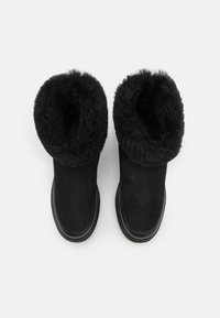 Sorte ankelstøvler i sued, med en bløt, fluffy fôr. Rund form og flat gummisåle, designet for varme og komfort.