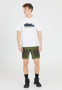 Herroutfit bestående av en vit bomullströja med berggrafik och gr�öna shorts med mörka fickor, tillsammans med svarta strumpor och kängor.