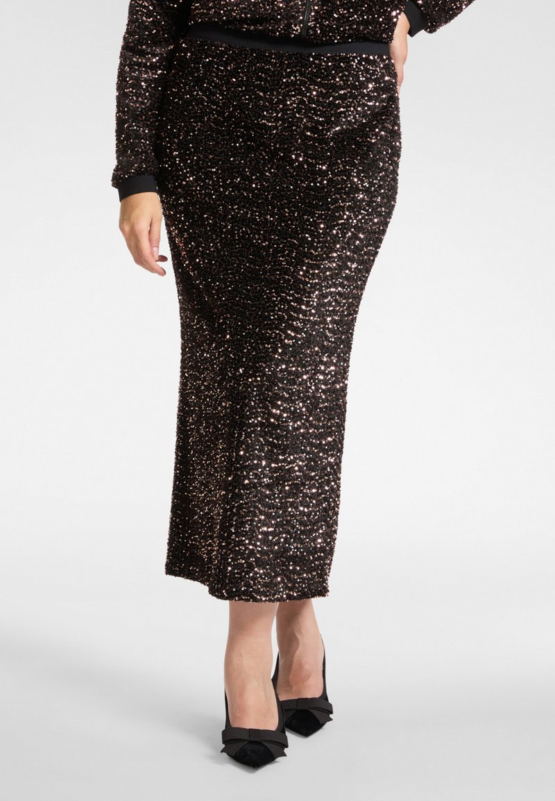 Jupe midi noire à sequins avec une silhouette ajustée et une texture lisse. Soulignée d'une ceinture et associée à des talons noirs ornés de nœuds.