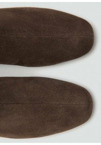Botines de ante marrón con una textura suave y punta redondeada, que presentan un diseño sin costuras y una silueta ligeramente afinada.