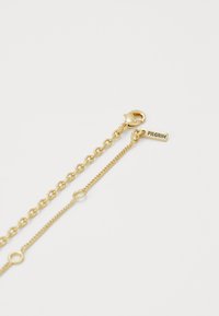 Goldkette mit einer Kombination aus Gliedern und zarter Textur, mit einem Karabinerverschluss und einem kleinen Anhänger, der mit "PILGRIM" graviert ist.