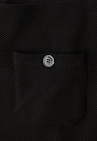 Černá texturovaná látka s malou kapsičkou, na které je šedý knoflík s nápisem "StreetOne". Výrazný vaflový vzor.